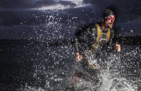 Homme habillé en tenu de plongée courant hors de la mer